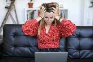 Young woman having problems with laptop while sitting on a leather couch